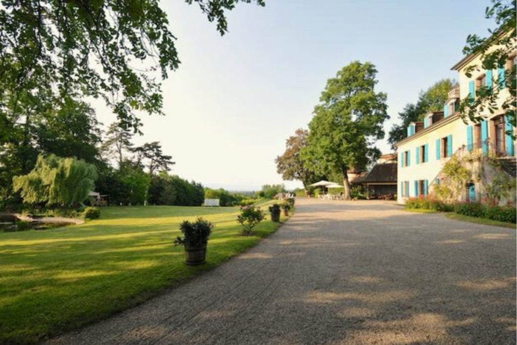 L’allée de gravier entre le parc et la façade aux volets bleus